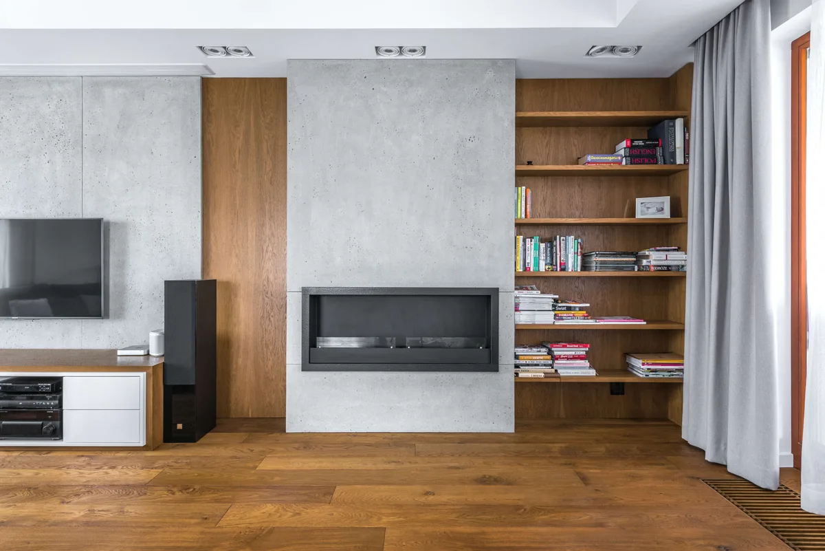 Salon z betonową ścianą i drewnianymi akcentami