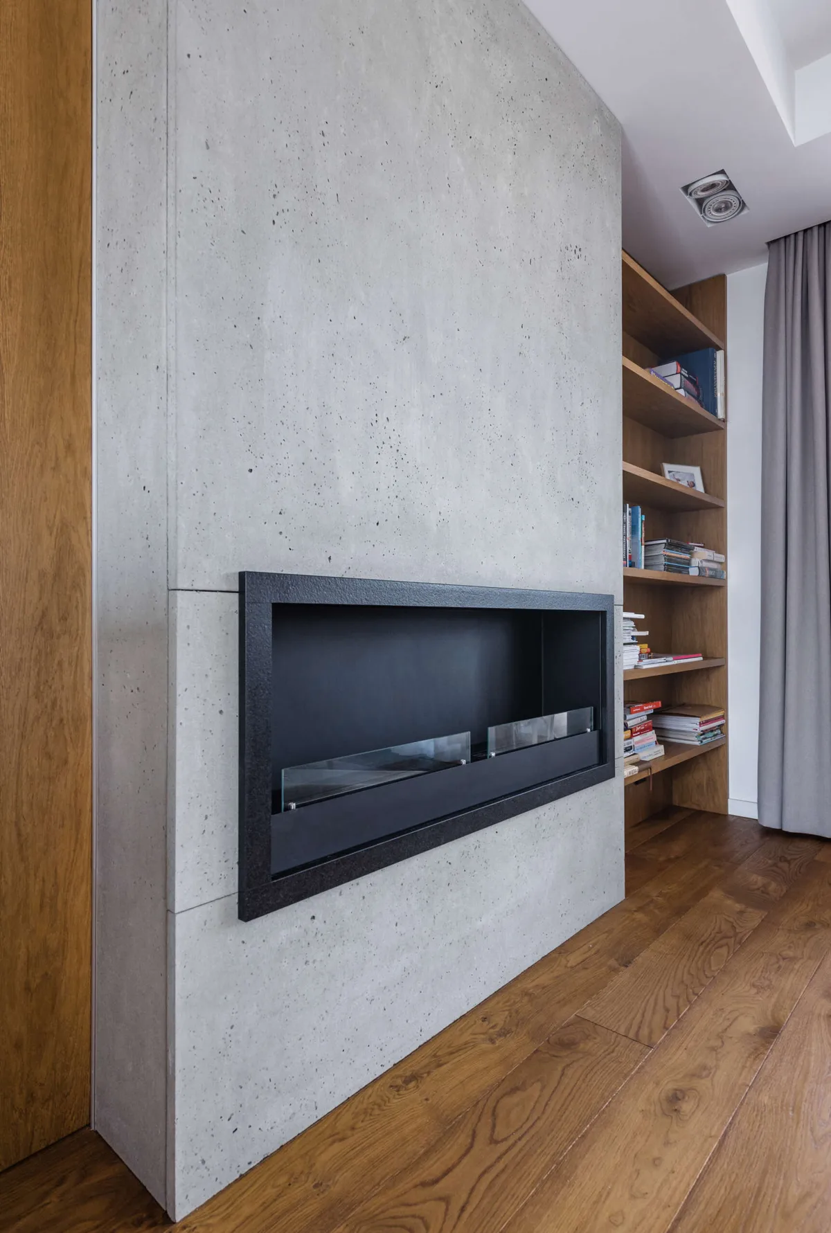 Betonowy kominek w nowoczesnym wnętrzu z drewnem